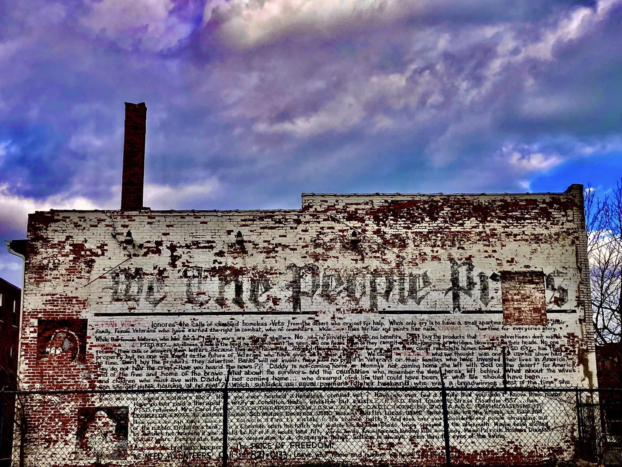 Brick wall mural under dramatic skies